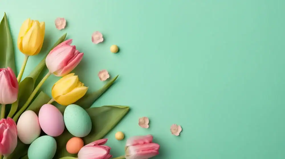 Pastel-colored Easter eggs, yellow and pink tulips, and small flower petals arranged on the left side of a light teal background, with ample empty space on the right.